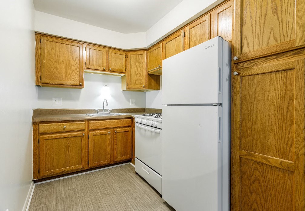 a kitchen with a white refrigerator and wooden cabinets